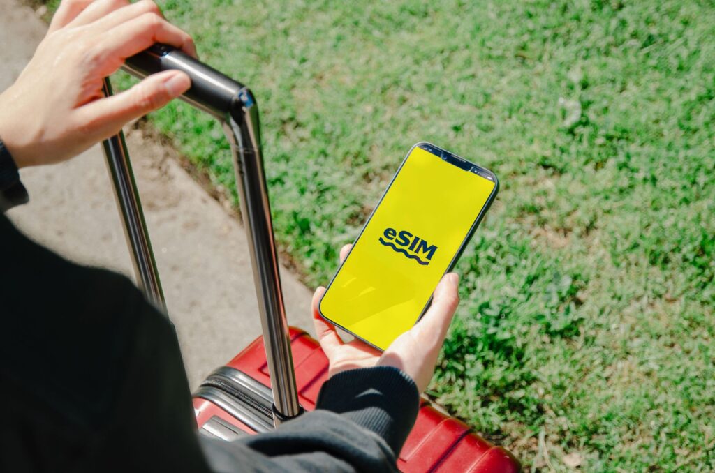 Hand holding a smartphone next to a SIM card representing budget UK mobile networks