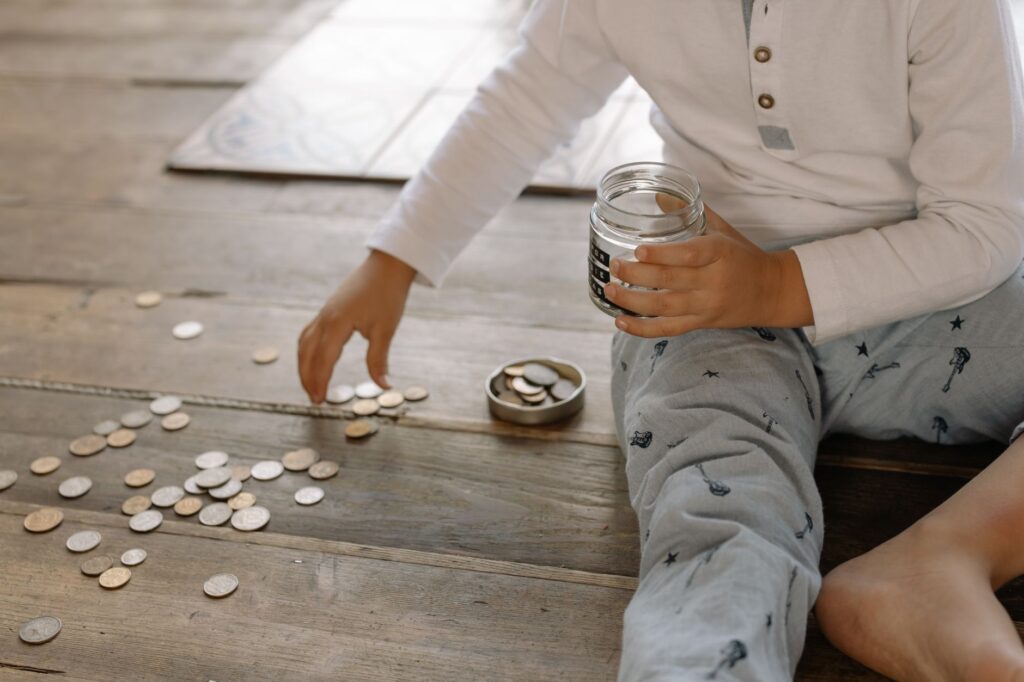 Parent and young child putting coins into a piggy bank, illustrating saving into a Junior ISA