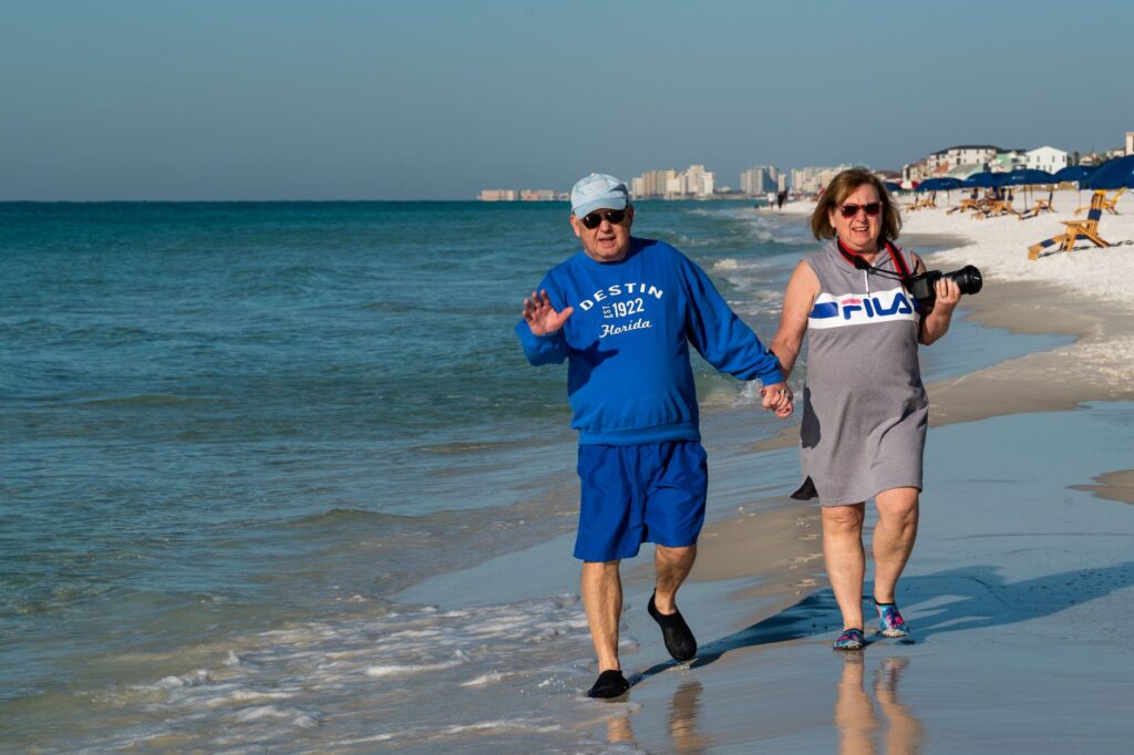 Relaxed retired UK couple walking on a beach, illustrating retirement lifestyle planning