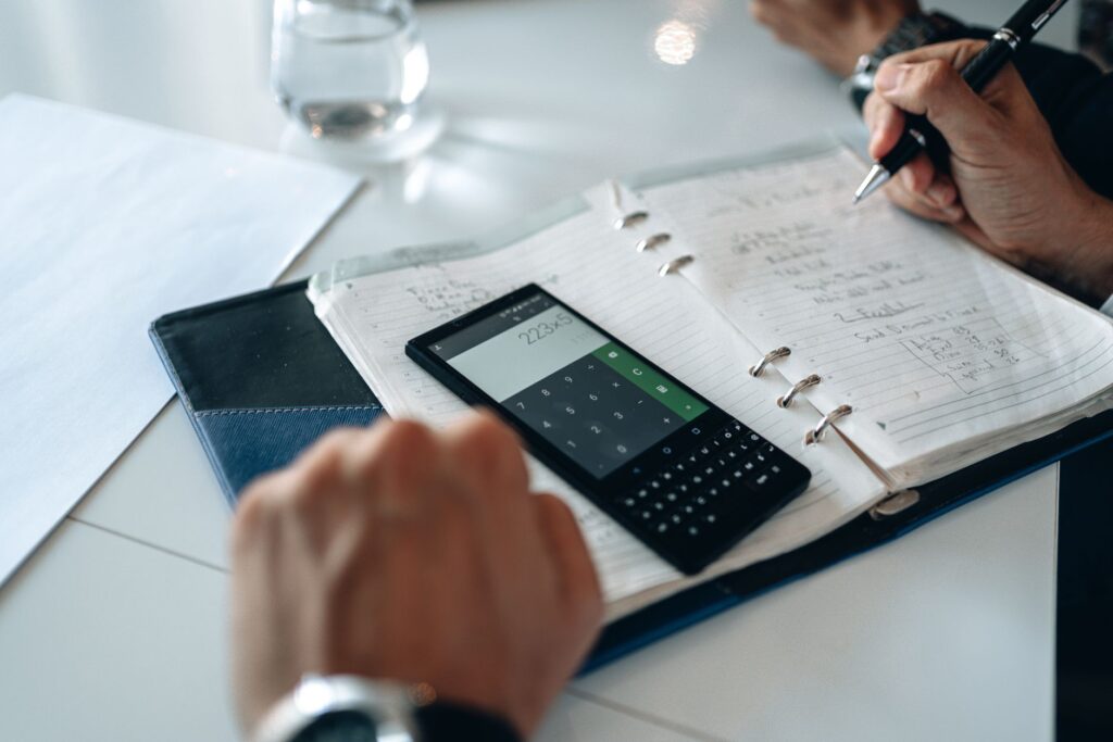 Smartphone beside a calculator and bills, comparing SIM-only and pay-monthly contract costs