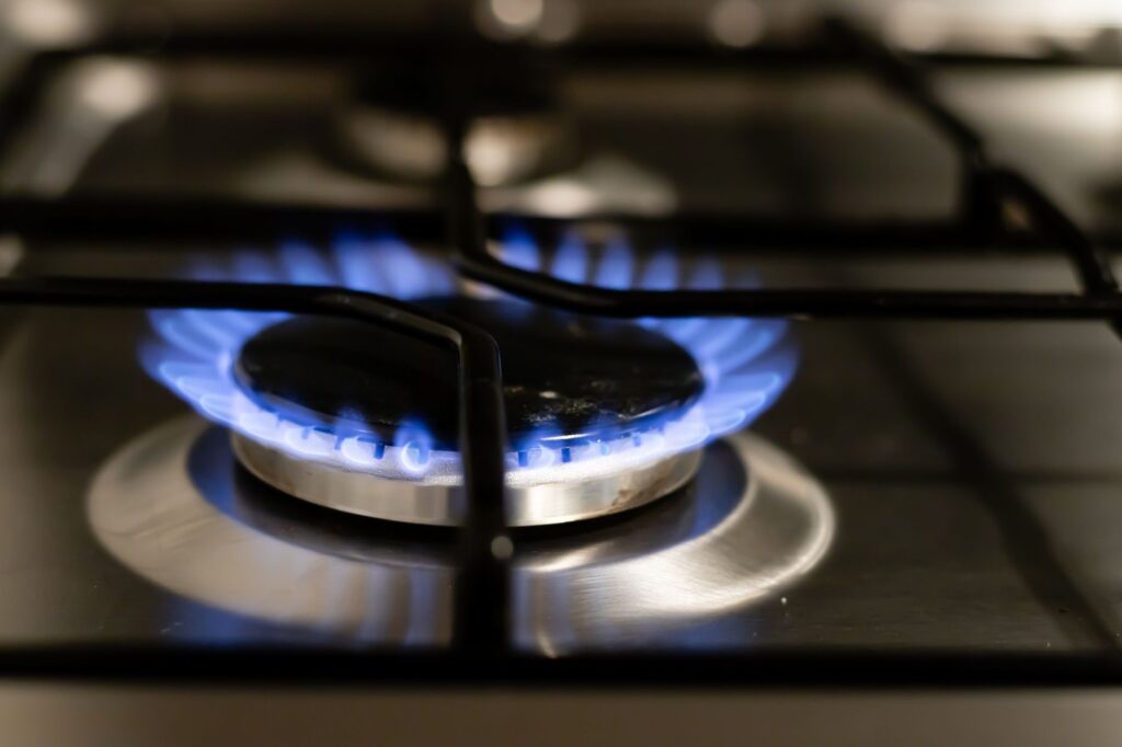 A blue gas hob flame on a home cooker representing UK household energy bills and the Ofgem price cap