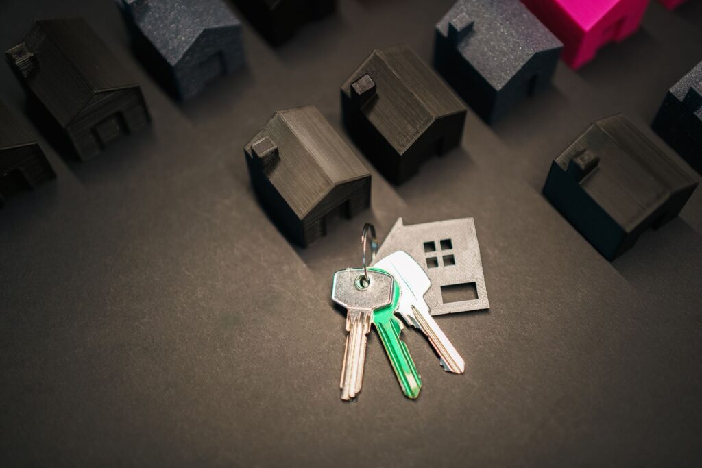 A set of house keys resting on a mortgage document beside a model home, representing UK mortgage rates in 2026