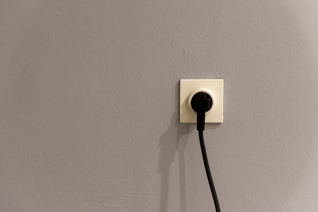 Old analogue landline telephone plugged into a wall socket in a UK home