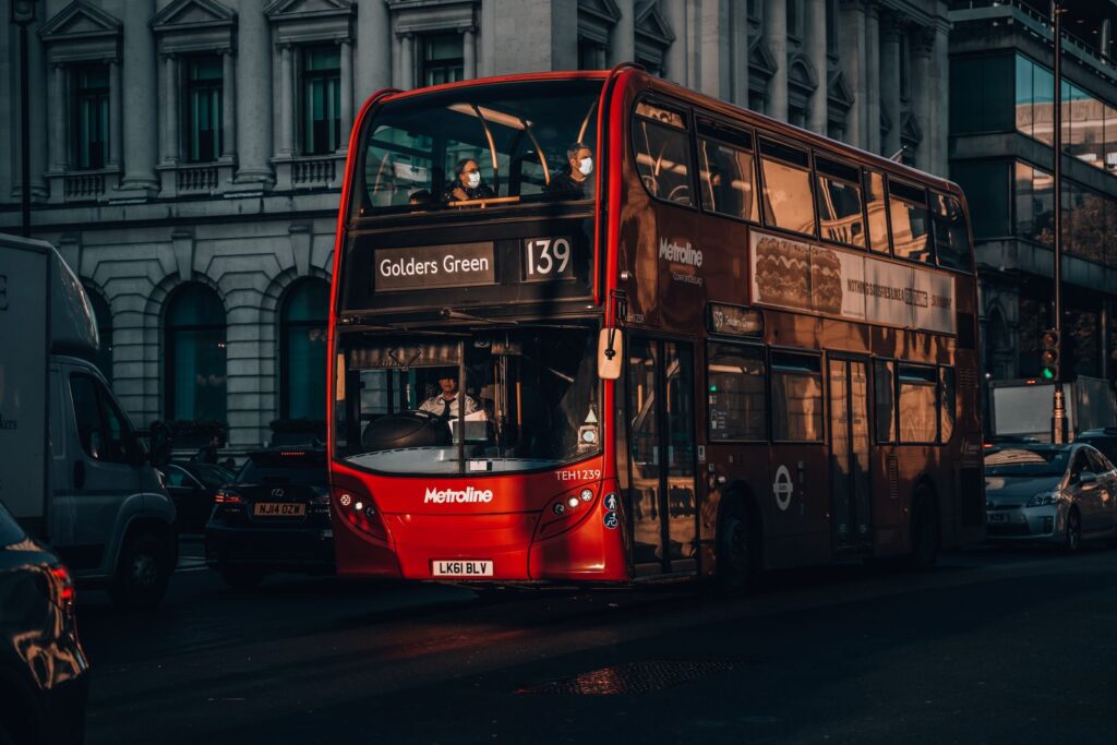 A red double-decker bus on a city street at dusk.