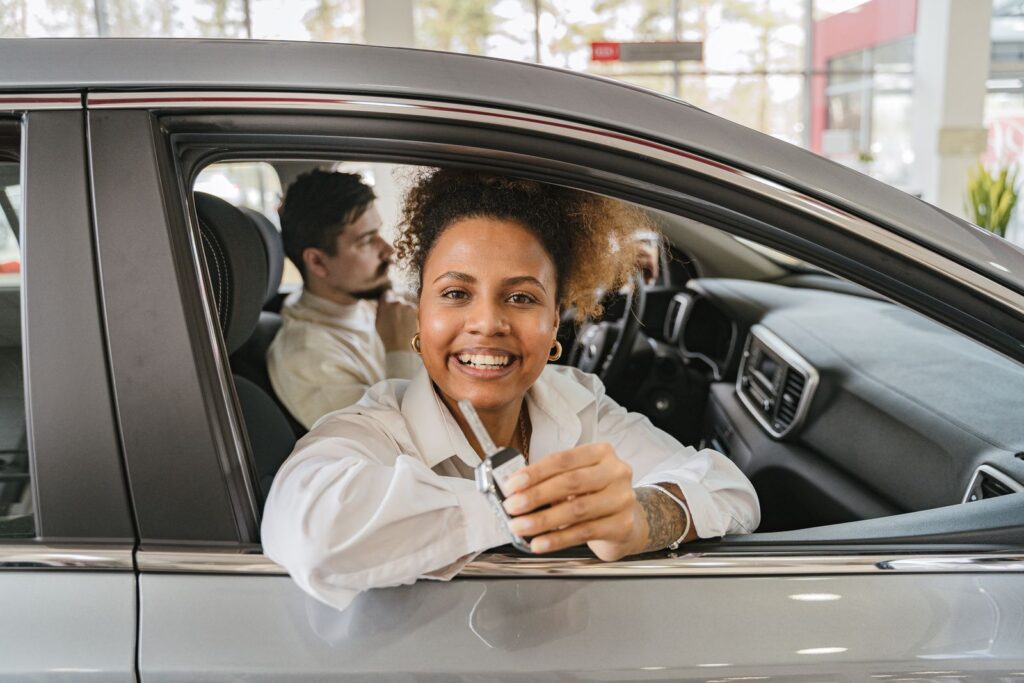 A driver sitting in a car holding the keys, after taking out a car finance agreement.