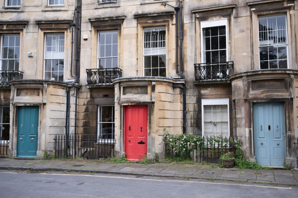 A row of identical British terraced houses with bay windows and front doors on a residential street.