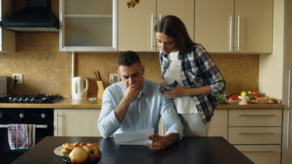 A couple at a kitchen table reading an energy bill together.