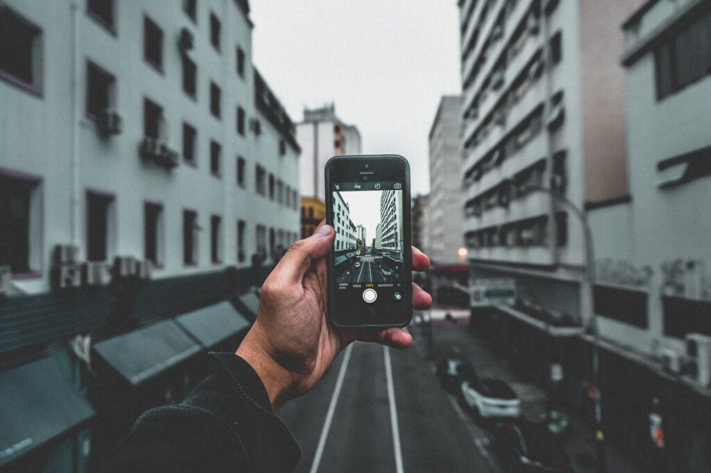 A traveller checking a smartphone map on a sunlit European street with a suitcase beside them.