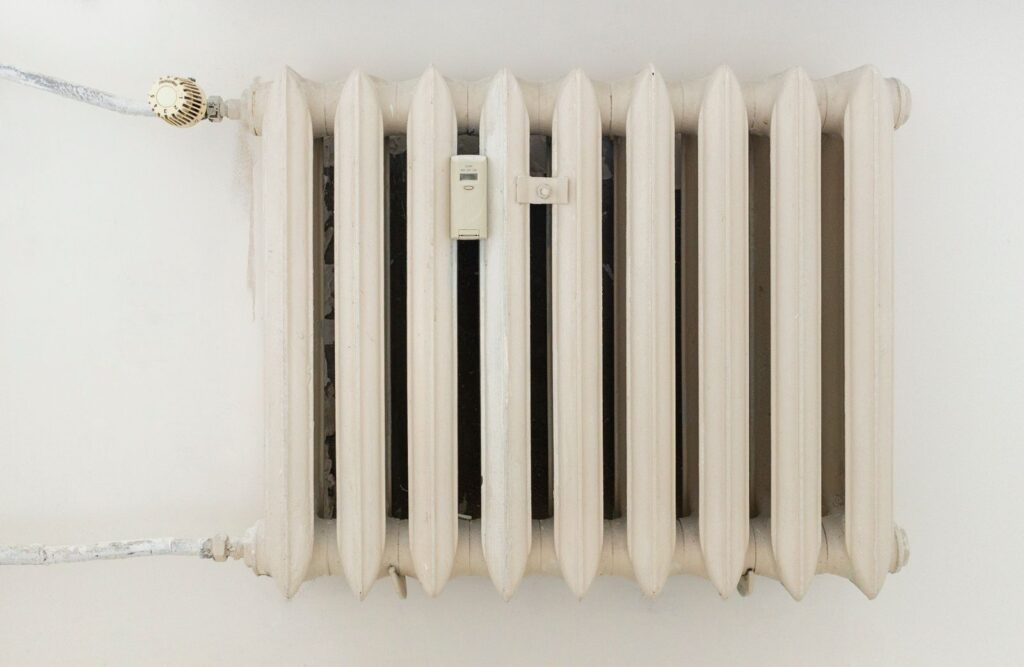 A domestic radiator with a thermostatic valve on the wall of a home.