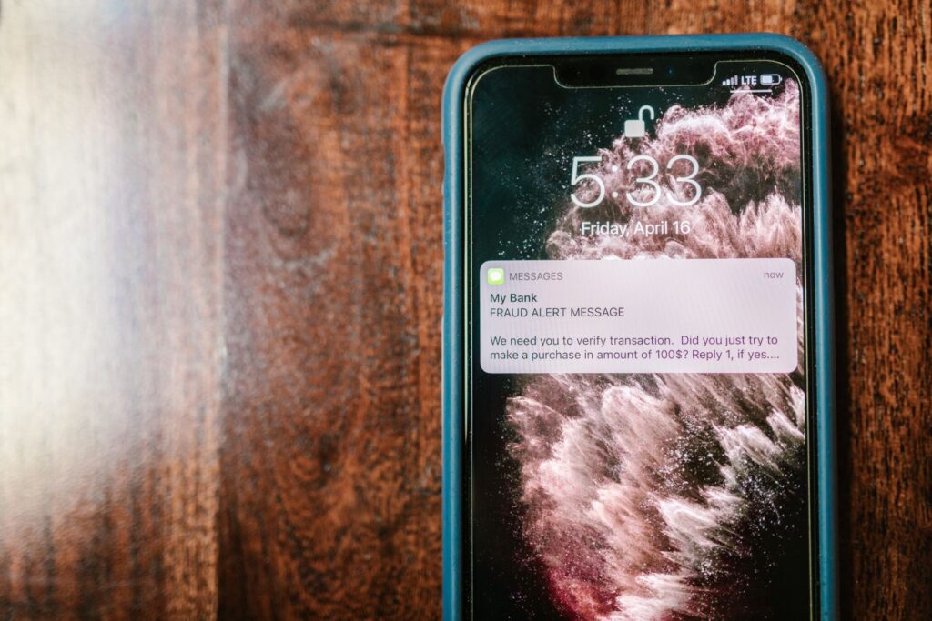 A smartphone lying on a wooden surface, its screen showing a fraud alert notification.