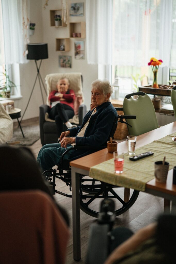 Two elderly people sitting and relaxing together in a bright care home room.