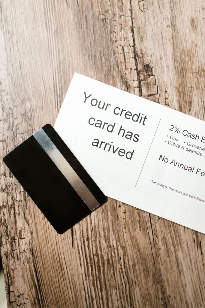 A credit card lying on a wooden table beside an opened letter.