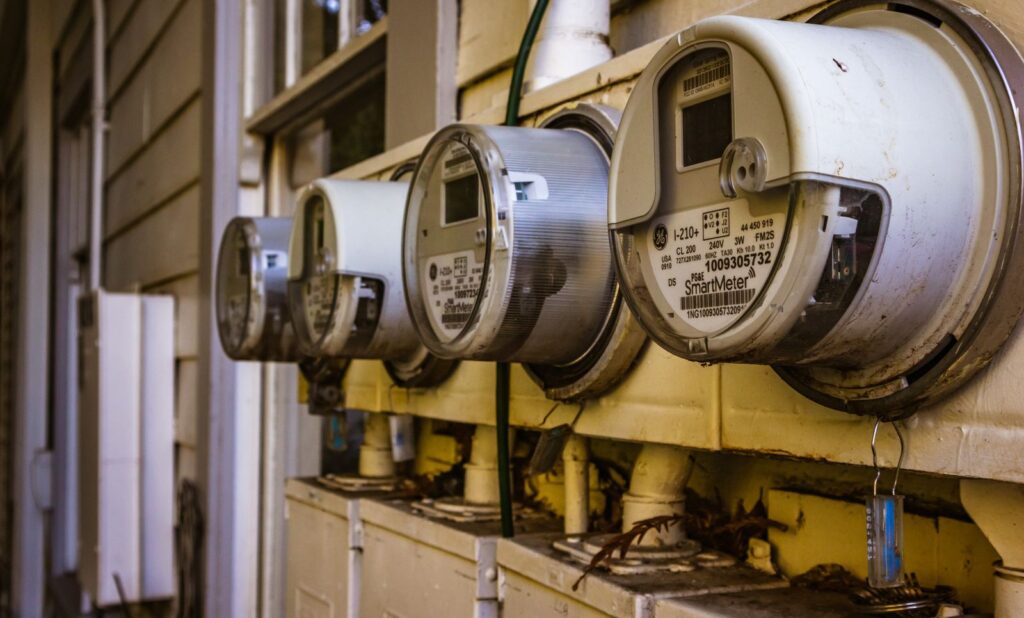 Several digital smart electricity meters mounted side by side on the outside wall of a residential building.